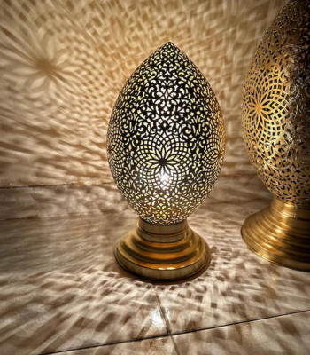 Hand-pierced Moroccan brass table lamp casting intricate floral light patterns on walls